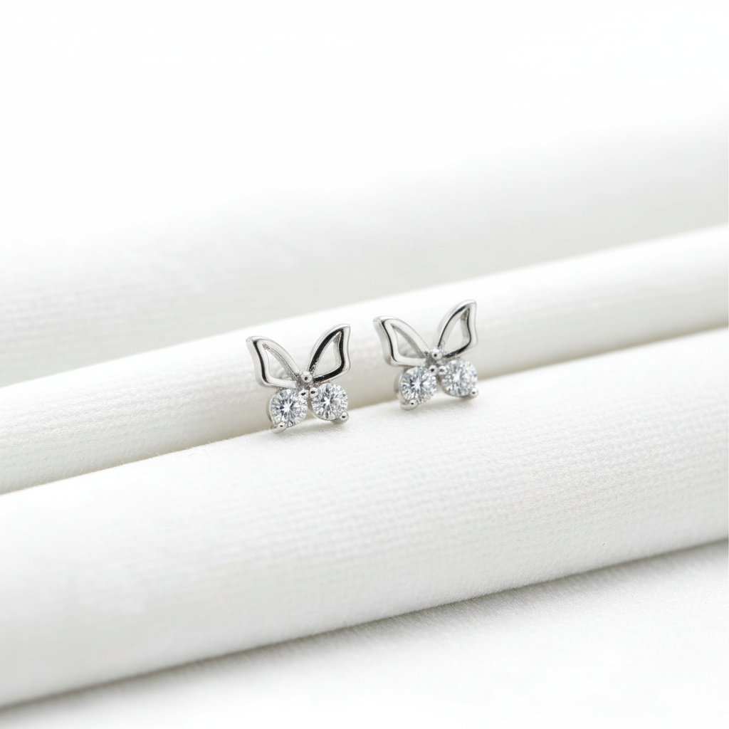 14K white gold butterfly ball stud earrings on white velvet, studio lighting