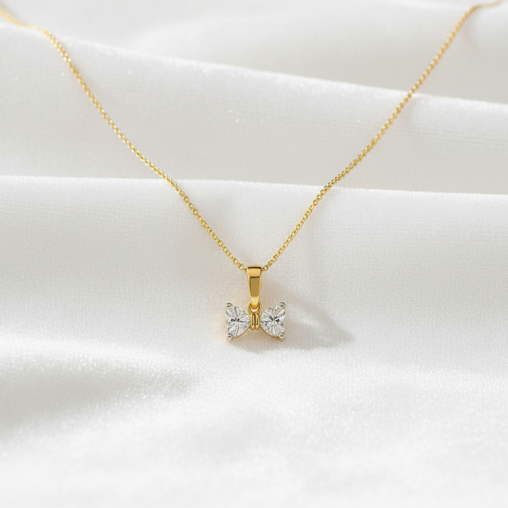 14K gold heart bow diamond pendant on white velvet, studio lighting