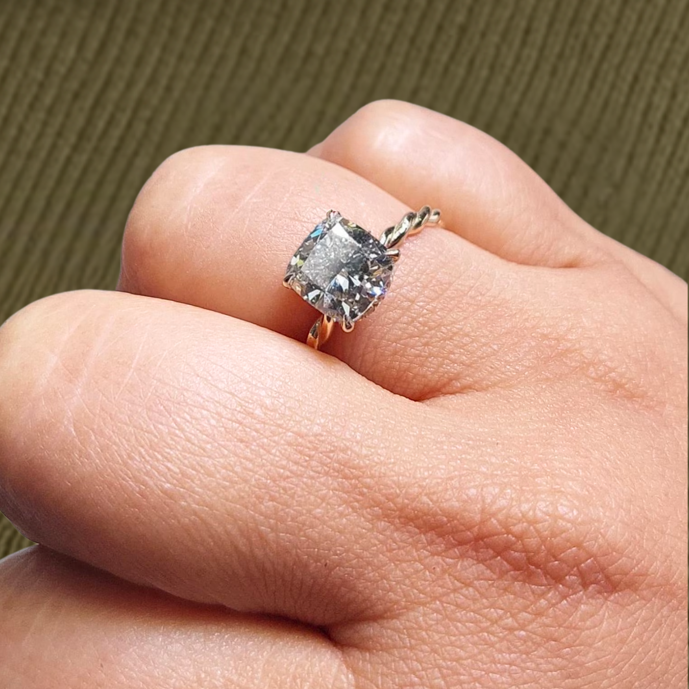 Close-up of a 2 ct cushion-cut lab-grown diamond engagement ring in 14k yellow gold on a hand