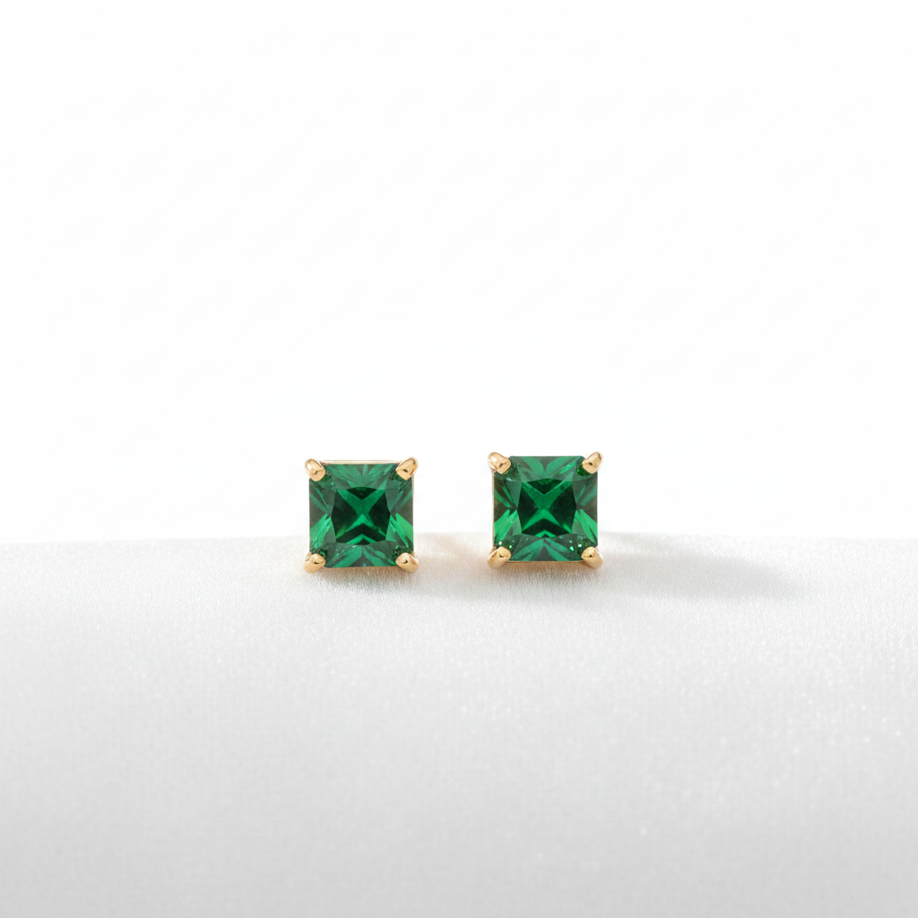 14K gold square emerald stud earrings on white velvet, studio lighting