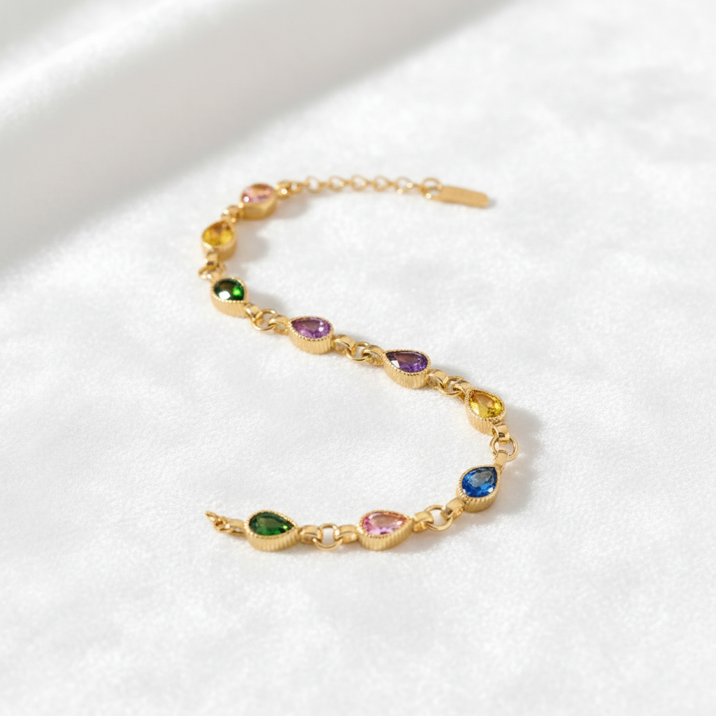 14K gold pear cut multi gemstone bracelet draped on white velvet, studio lighting