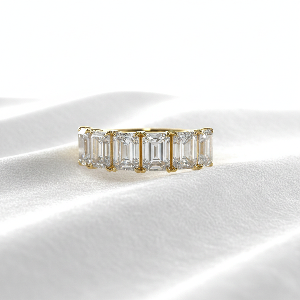14K gold five emerald cut diamond wedding ring on wavy white velvet, studio lighting