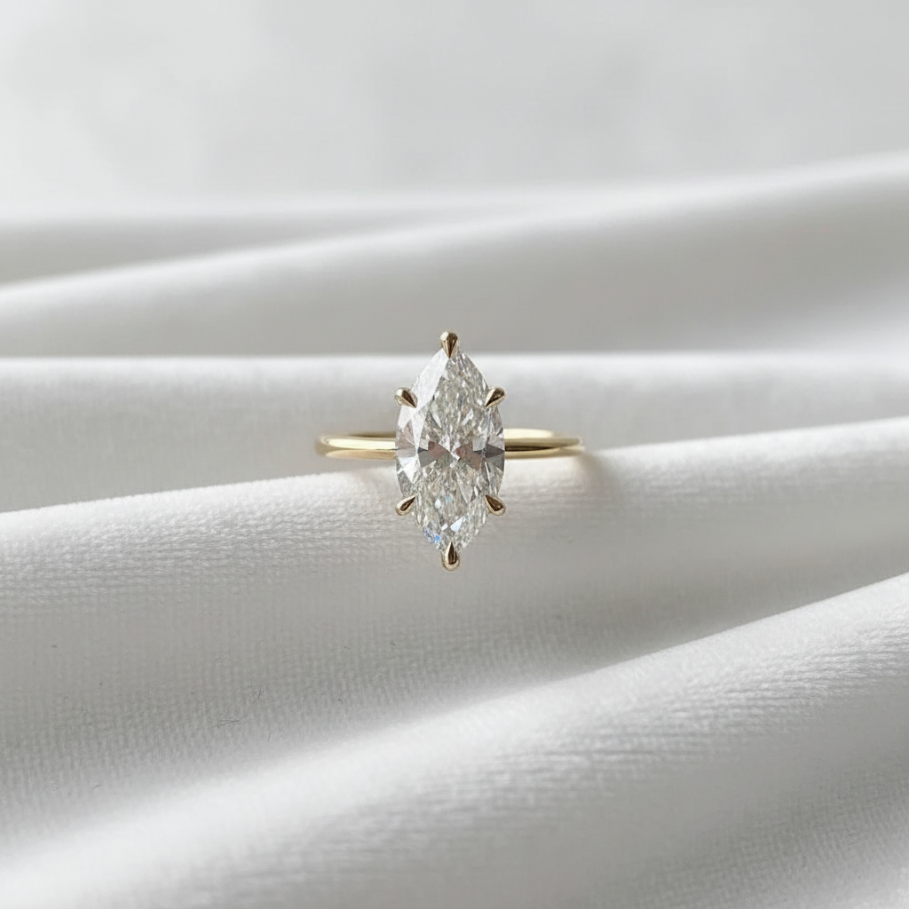 14K gold marquise cut lab diamond solitaire engagement ring on wavy white velvet, studio lighting