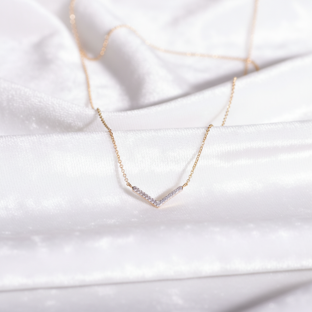 14K gold chevron V shape diamond necklace on wavy white velvet, studio lighting