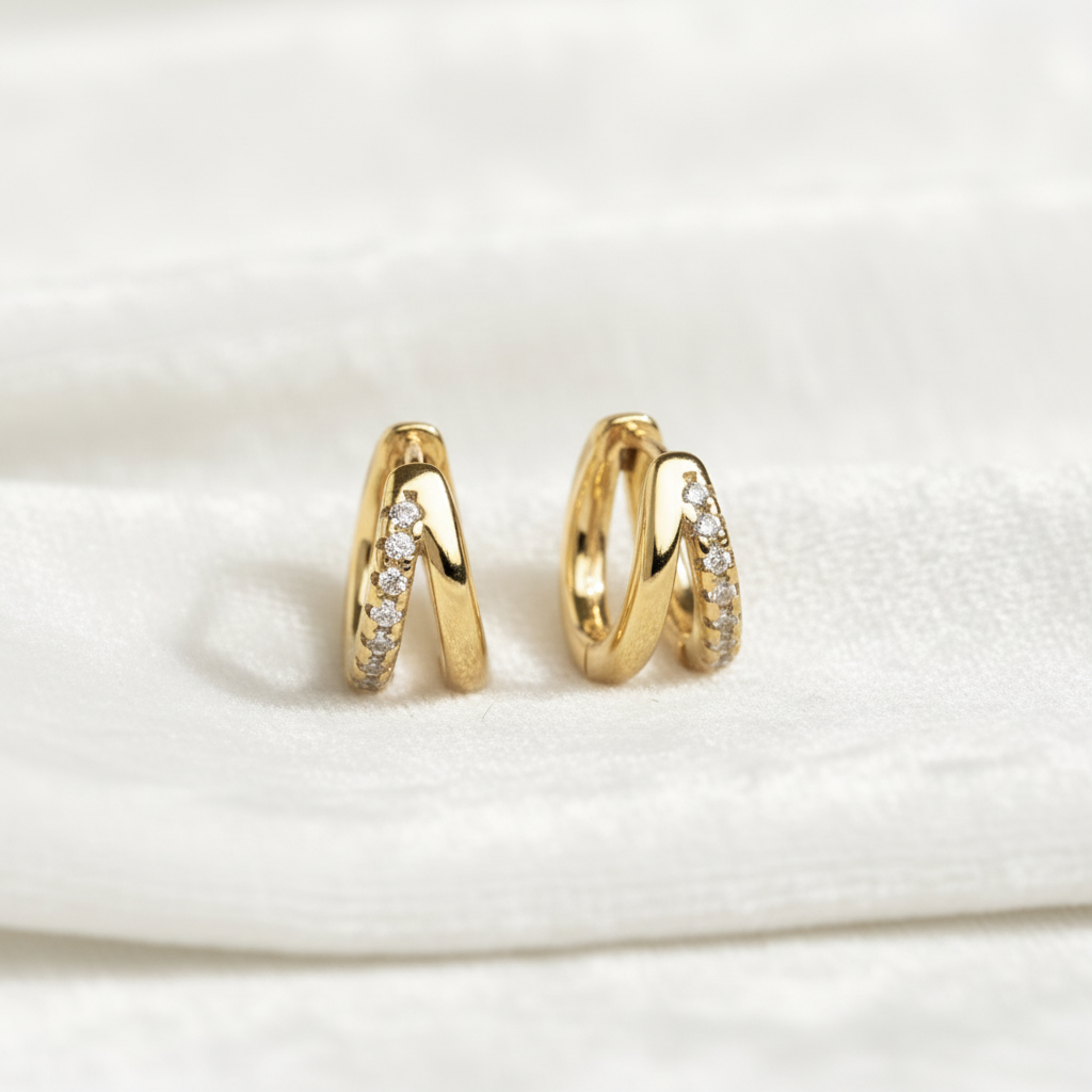 14K gold double hoop diamond earrings on white velvet, studio lighting