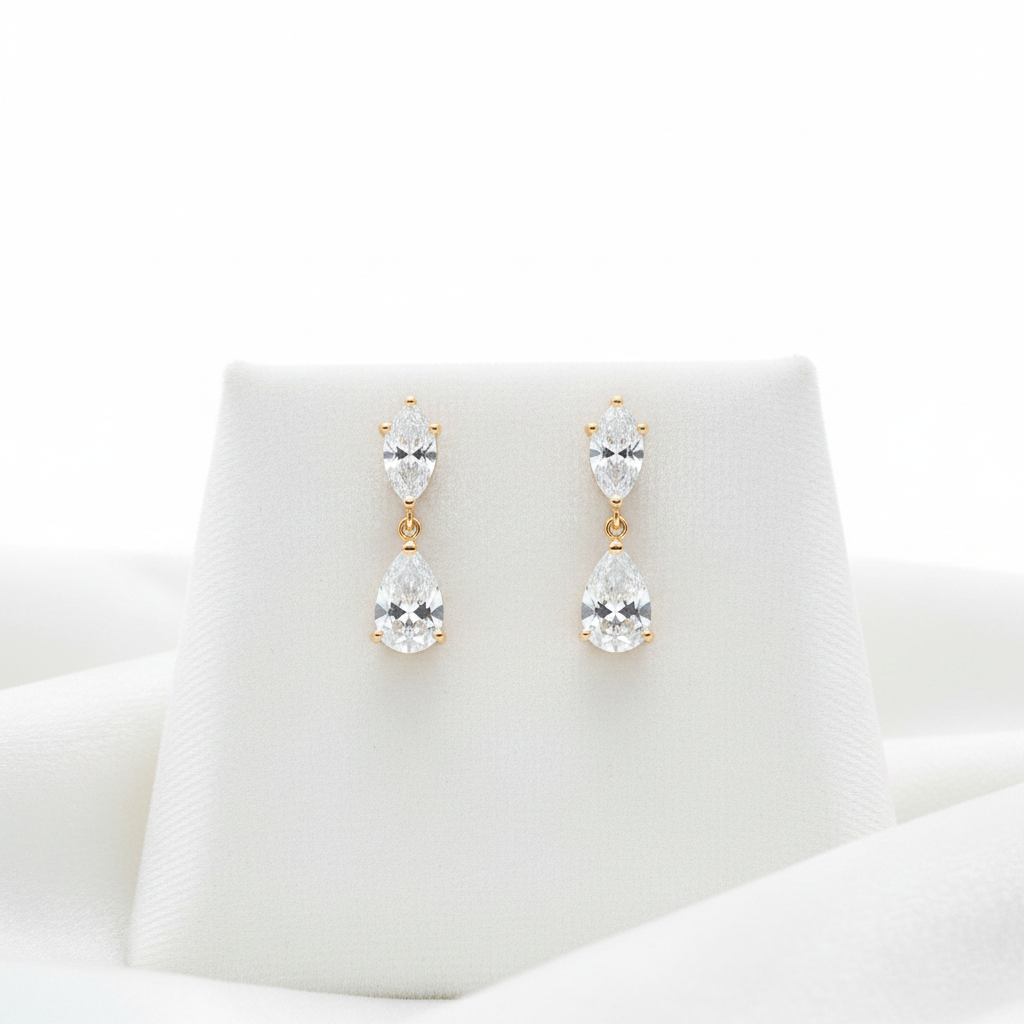 14K gold pear diamond drop dangle earrings on white velvet, studio lighting